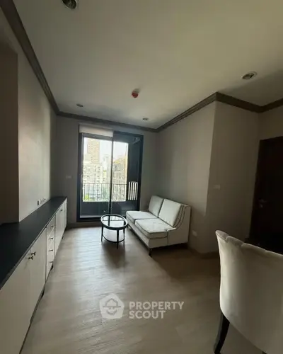 Modern living room with city view, featuring sleek furniture and large window for natural light.