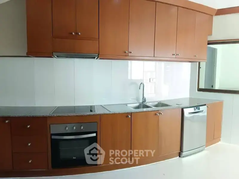 Modern kitchen with wooden cabinets, built-in oven, and dishwasher in a sleek design.