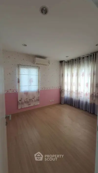 Charming bedroom with wooden flooring and large windows for natural light.