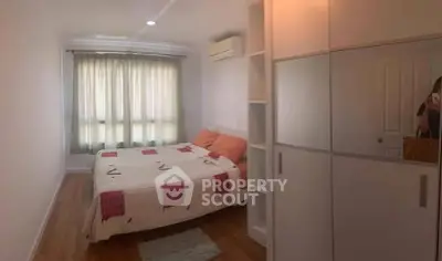 Cozy bedroom with wooden flooring, large window, and modern wardrobe in a bright apartment.