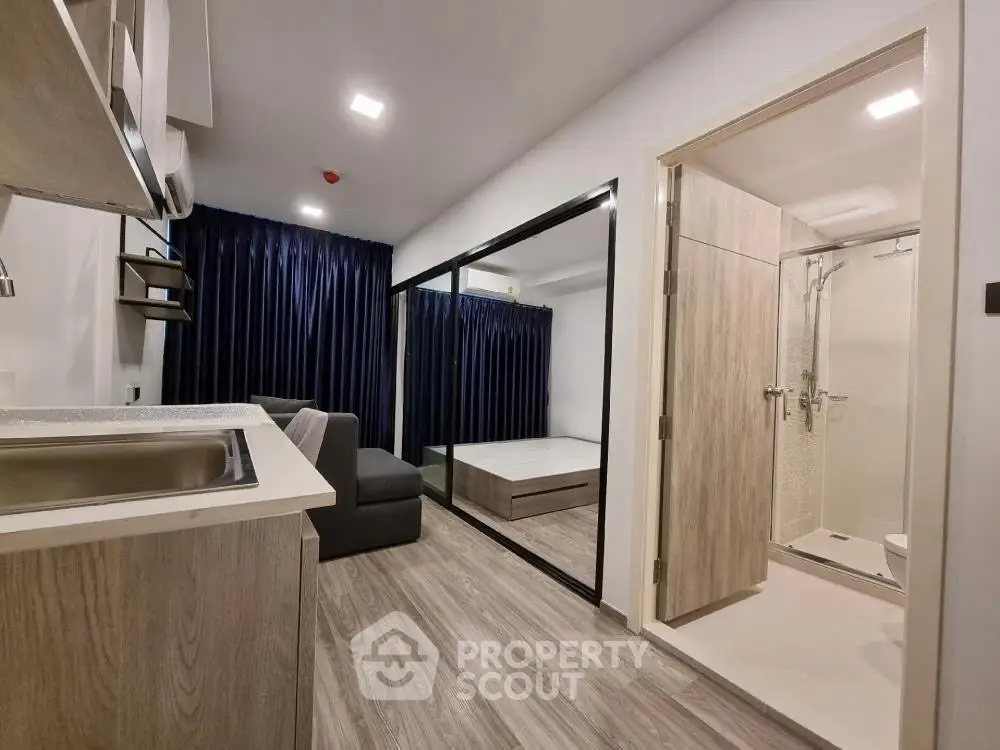 Modern studio apartment with open layout, featuring a compact kitchen and cozy living area.