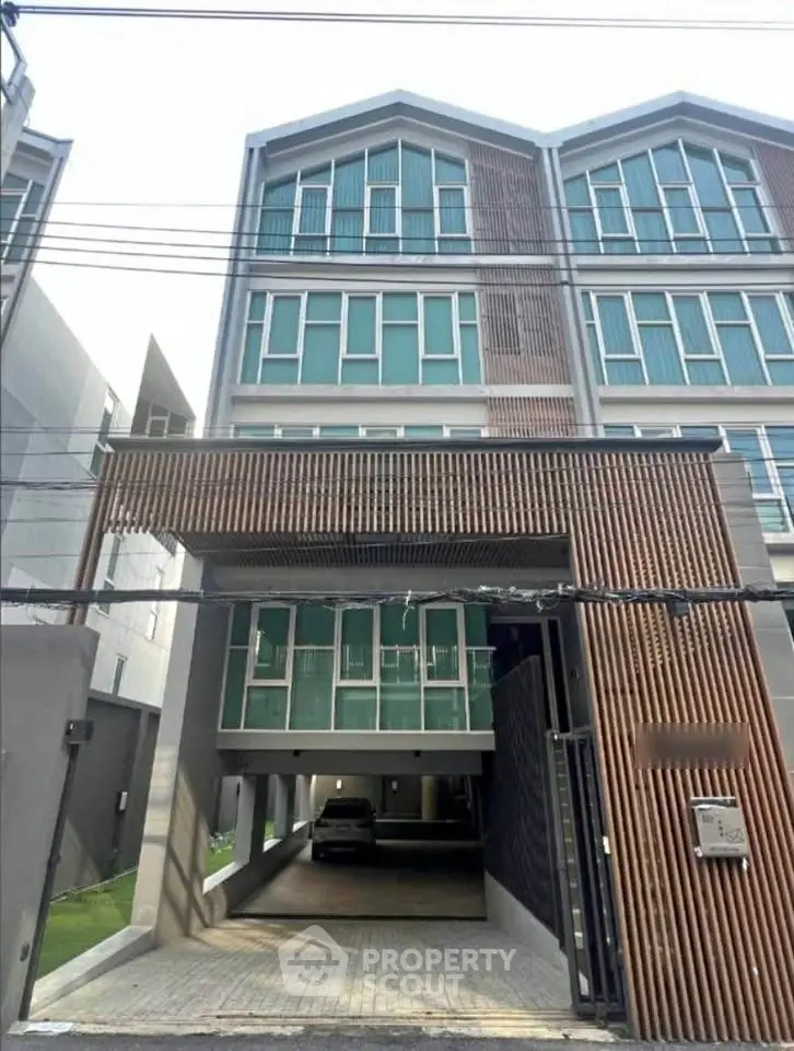 Modern multi-story building with unique architectural design and spacious parking area.