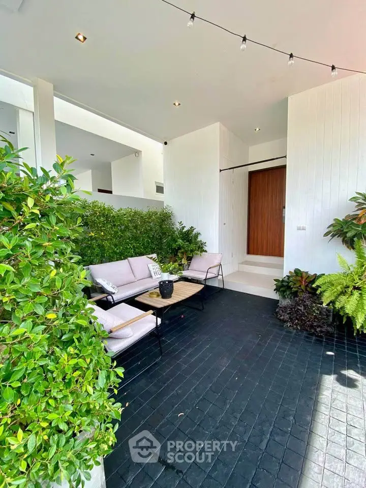 Chic modern entrance with lush greenery and cozy seating area.