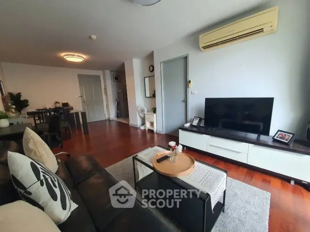 Spacious living room with modern decor and air conditioning, featuring a cozy seating area and entertainment setup.