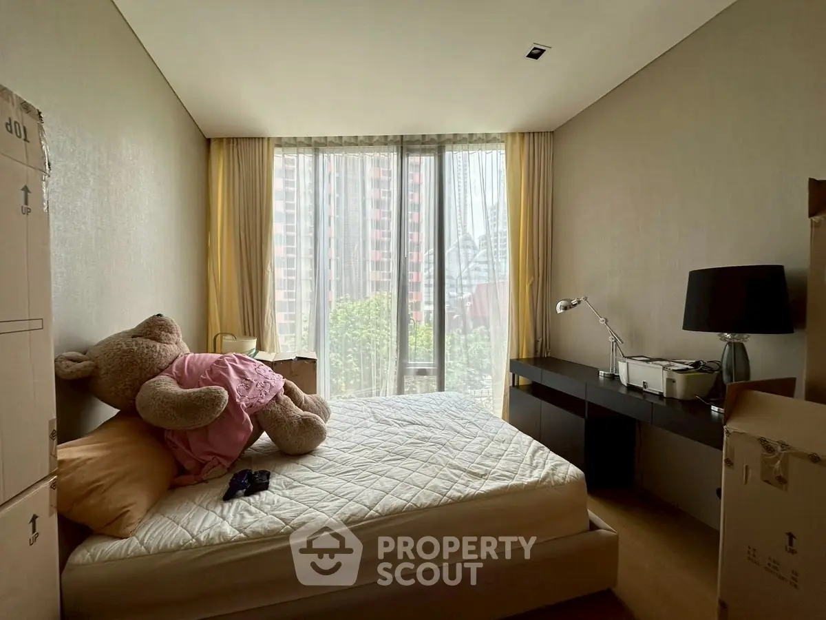 Cozy bedroom with large window and teddy bear, perfect for relaxation.