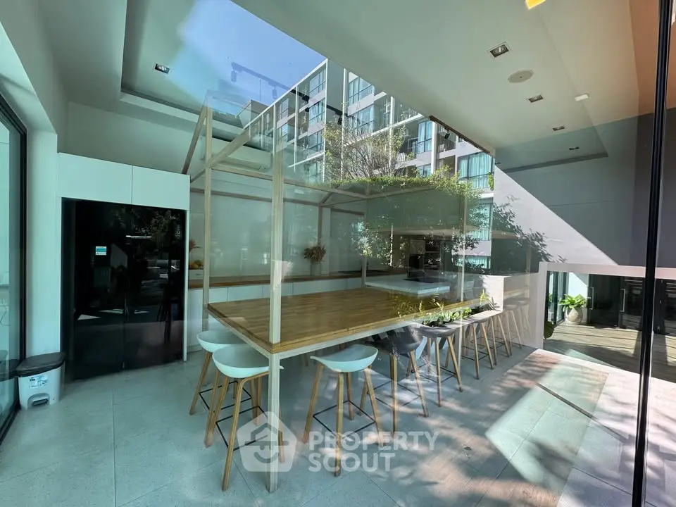Modern communal dining area with large windows and natural light in a contemporary building.