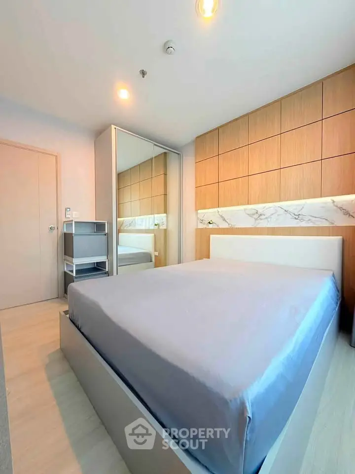 Modern bedroom with sleek design, featuring a large mirror and stylish wooden accents.