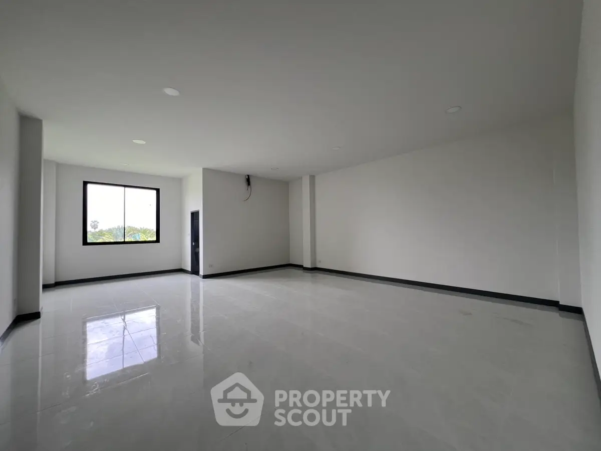 Spacious empty room with large window and glossy tiled floor, perfect for customization.