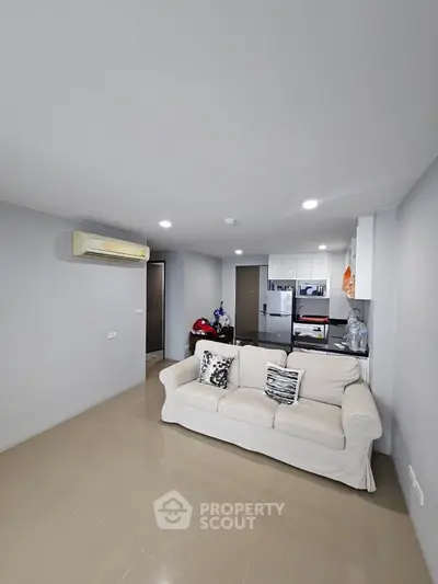 Modern living room with cozy sofa and sleek kitchen in open layout apartment.