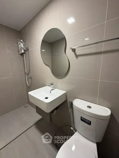 Modern bathroom with sleek fixtures and unique mirror design in contemporary apartment.