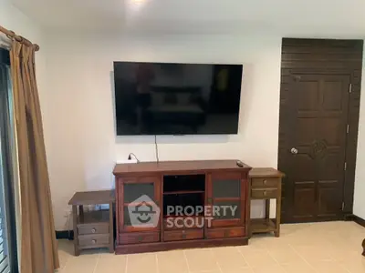 Spacious living room with modern TV setup and elegant wooden furniture