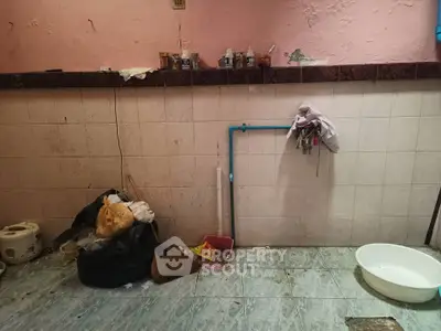 Unkempt kitchen area with clutter and visible plumbing issues.