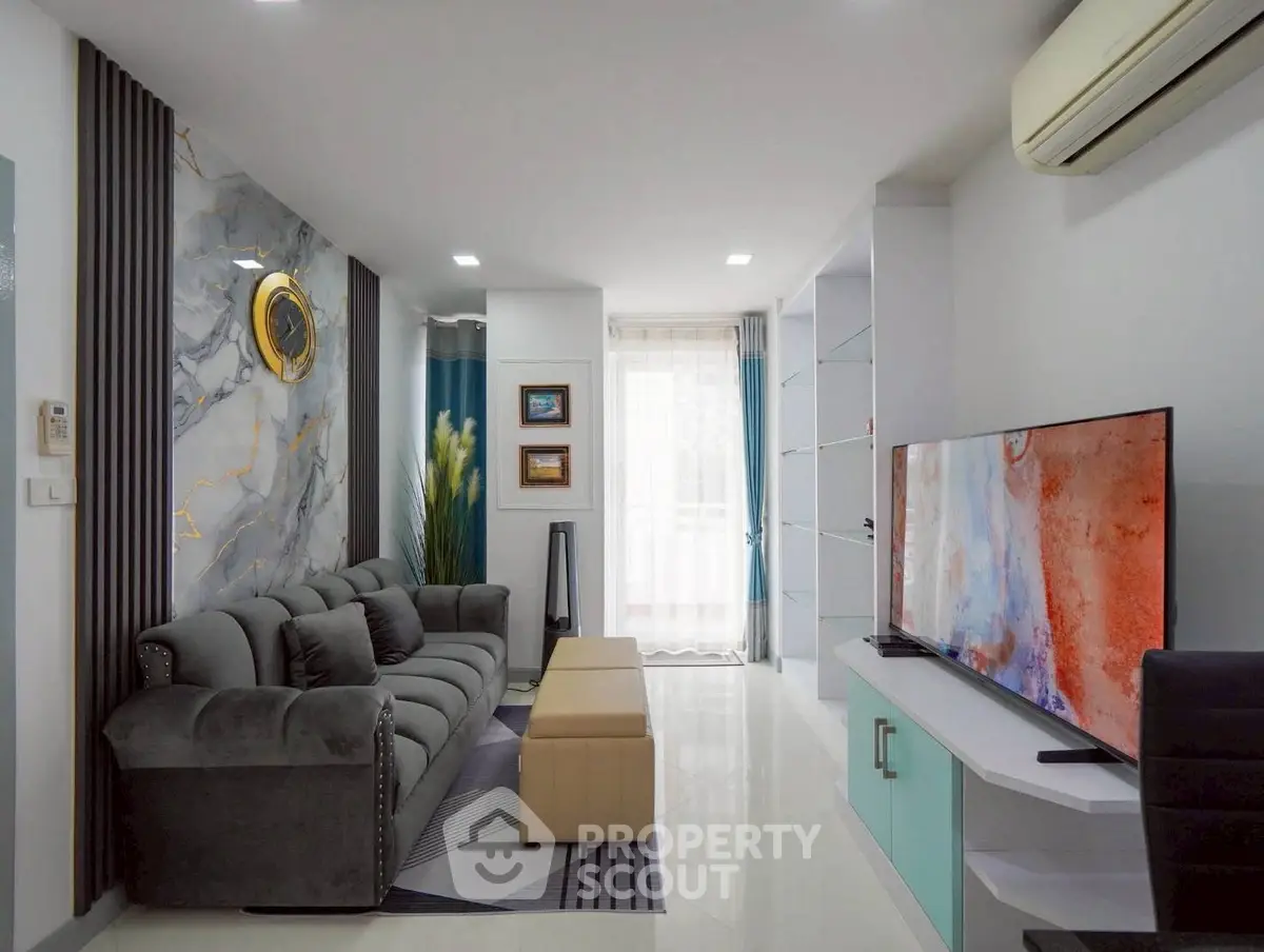 Modern living room with stylish decor, large TV, and comfortable seating in a bright apartment.