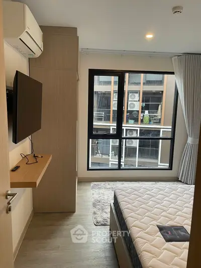 Modern bedroom with large window and wall-mounted TV in a stylish apartment.