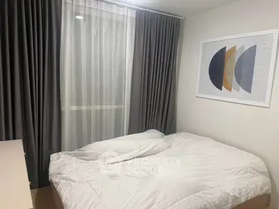 Cozy bedroom with modern decor and large window, perfect for relaxation.
