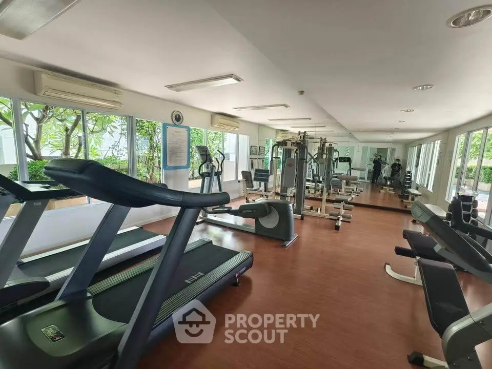 Spacious gym with modern equipment and large mirrors in a well-lit room.