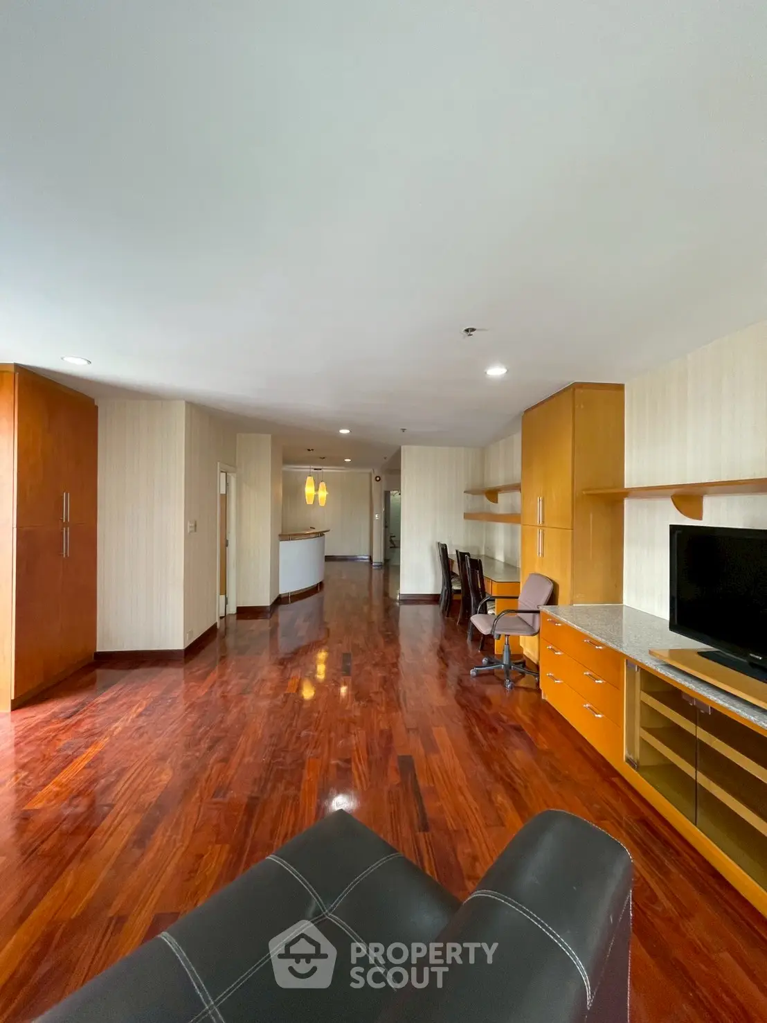 Spacious living room with glossy wooden floors and built-in desk area