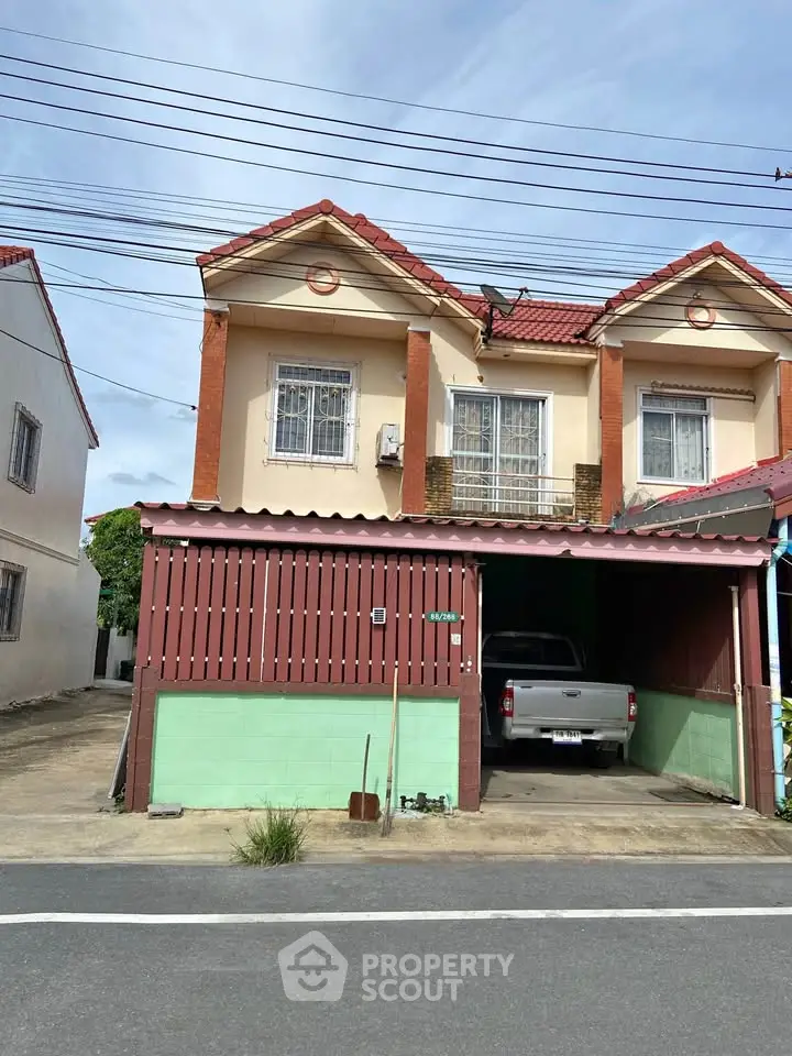 Charming two-story townhouse with a carport and traditional red-tiled roof, perfect for family living.