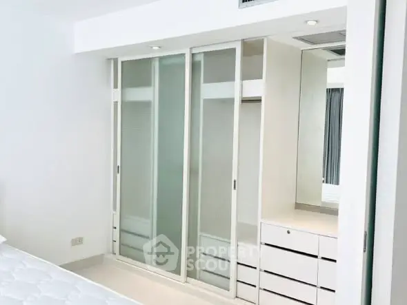 Modern bedroom with sleek built-in wardrobe and ample storage space.