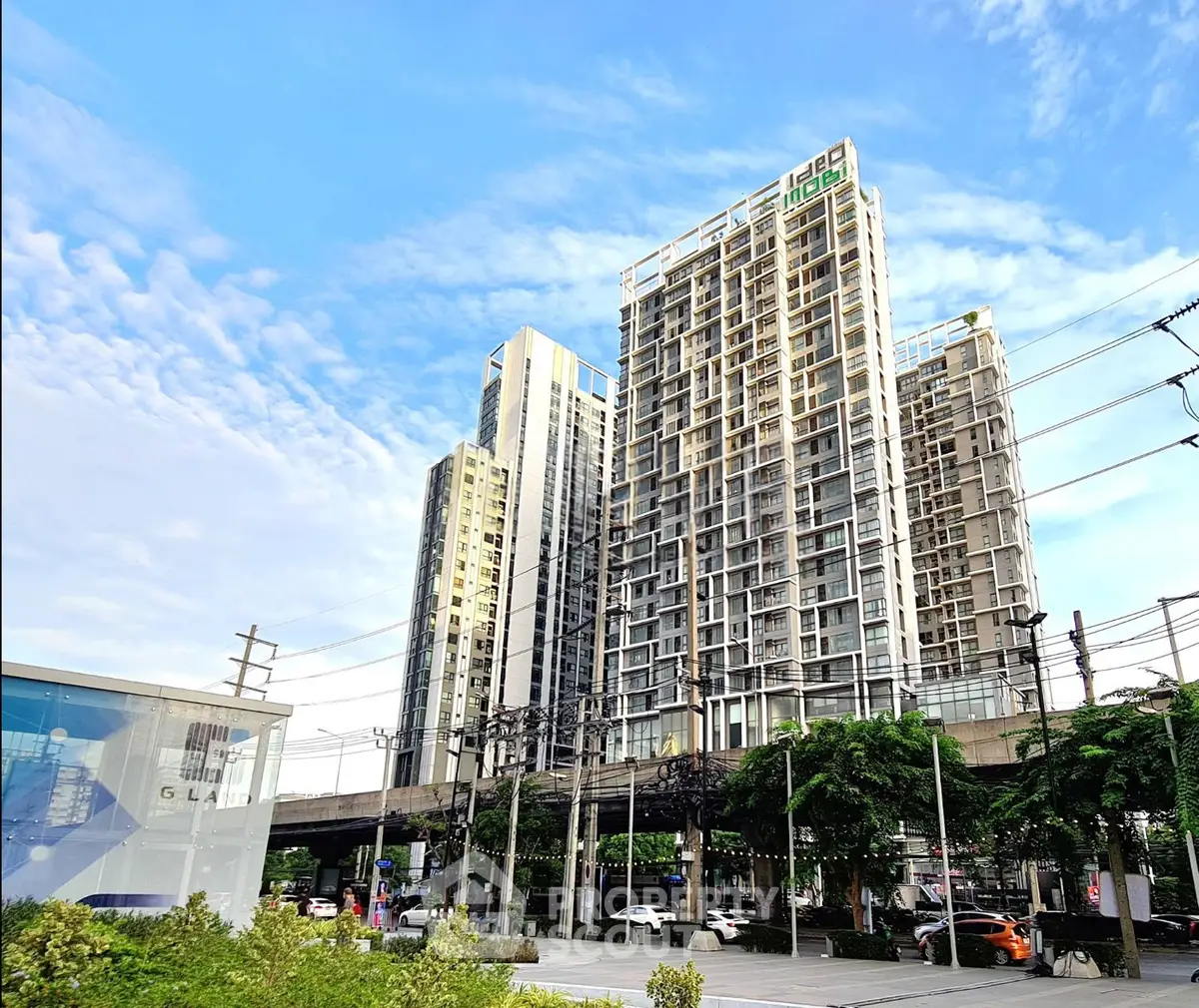 Modern high-rise residential building with clear blue sky and lush greenery, showcasing urban living at its finest.