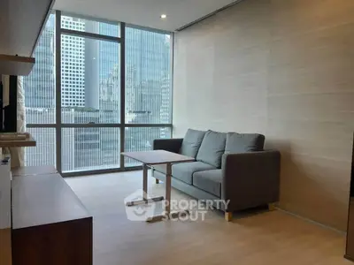 Modern living room with large windows and city view, featuring a cozy gray sofa and sleek wooden flooring.