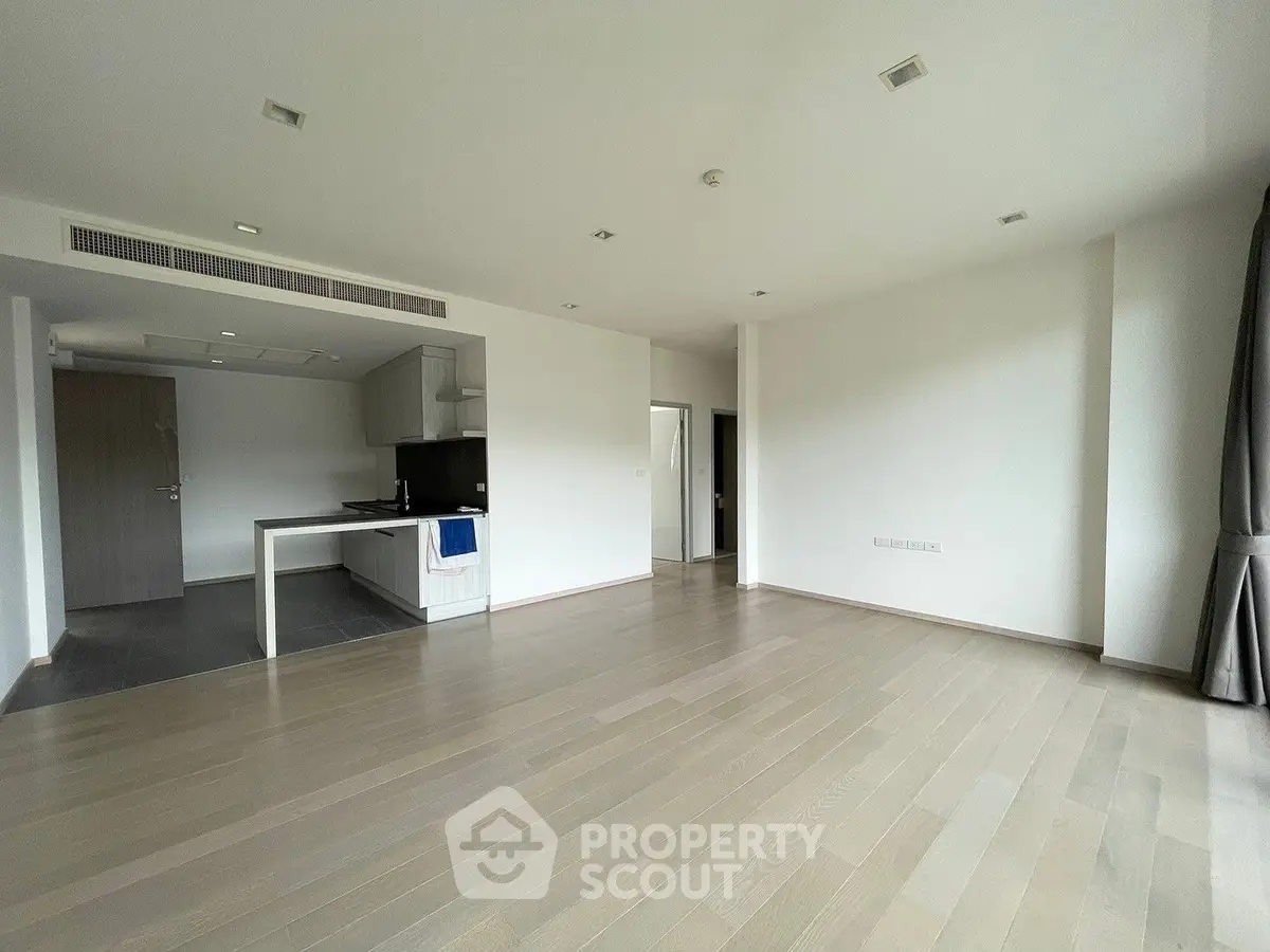 Spacious open-plan living area with modern kitchen, ample natural light, and sleek wooden flooring, ideal for entertaining and comfortable living.
