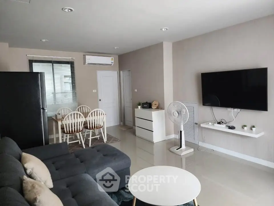 Modern living room with sleek furniture and wall-mounted TV in a stylish apartment.