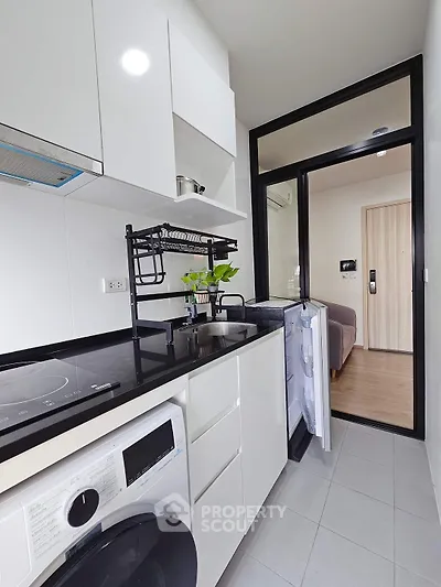 Modern kitchen with sleek appliances and washing machine in compact layout