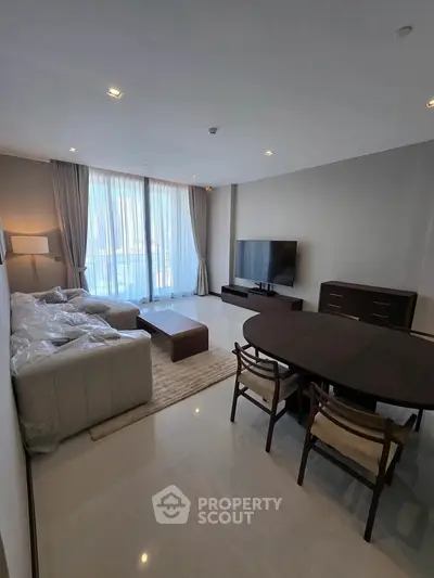 Spacious modern living room with large windows and elegant furniture in a high-rise apartment.
