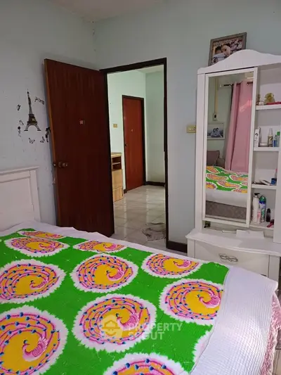 Cozy bedroom with colorful bedding and mirrored dresser in a charming home.