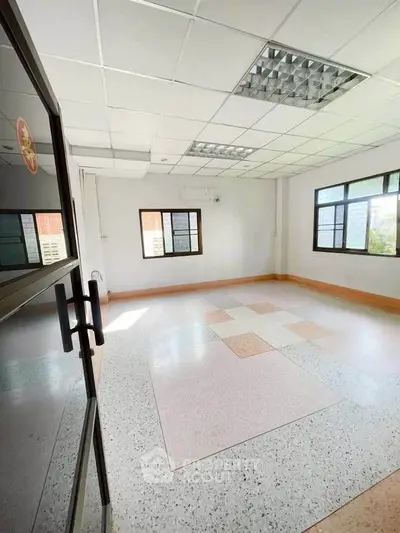Spacious empty room with large windows and tiled floor, ideal for customization.