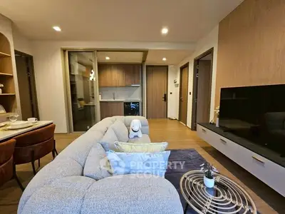 Modern living room with stylish decor and open kitchen layout, featuring cozy seating and elegant dining area.