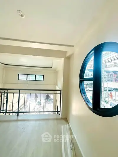 Modern loft space with unique circular window and sleek railing design