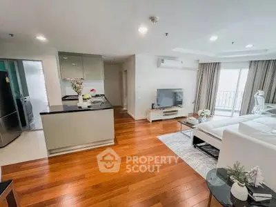 Spacious modern living room with open kitchen and hardwood floors in a stylish apartment.