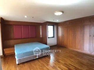 Spacious bedroom with wooden flooring and built-in wardrobes in a modern apartment.