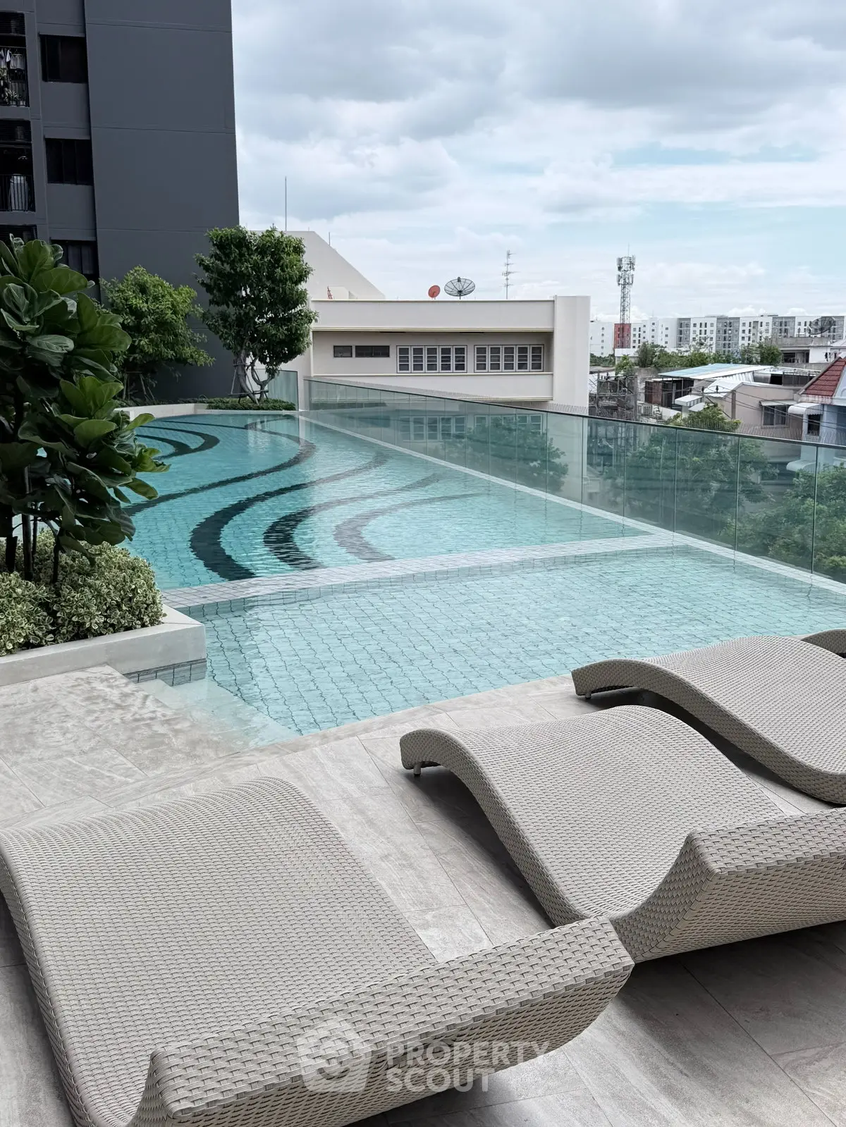 Luxurious rooftop pool with modern lounge chairs and city view, perfect for relaxation and leisure.