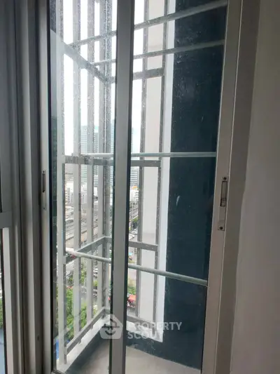 Modern balcony with glass doors offering city views in a high-rise building.