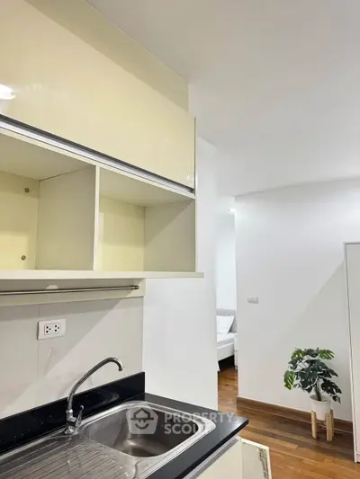Modern kitchen with sleek cabinetry and stainless steel sink in a bright apartment.