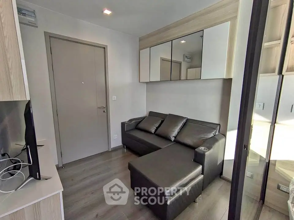 Modern compact living room with sleek black sofa and mirrored cabinets