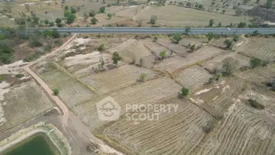 Expansive aerial view of agricultural land with road access, ideal for development opportunities.