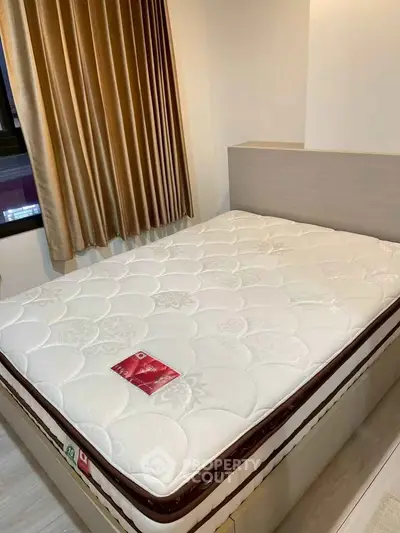 Cozy bedroom with a comfortable mattress and elegant curtains, perfect for restful nights.