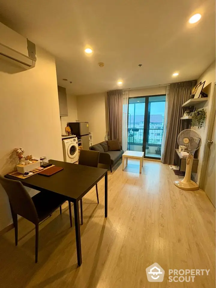 Modern living room with balcony view, wooden flooring, and stylish furniture in a cozy apartment.