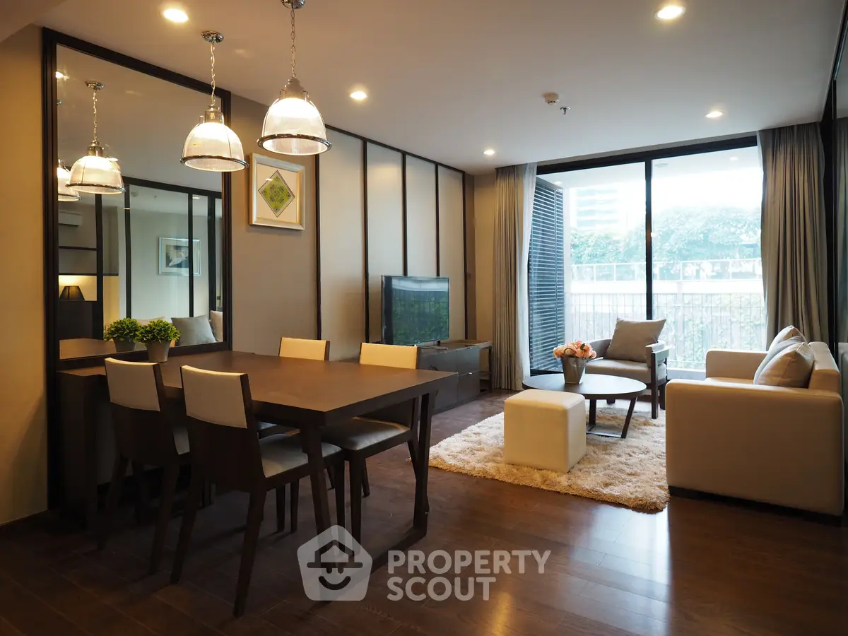 Modern living room with elegant dining area and large windows offering natural light and a cozy atmosphere.