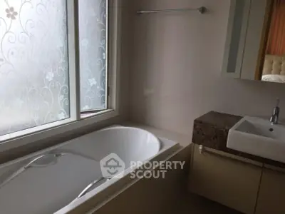 Elegant bathroom with modern fixtures and frosted window for privacy.