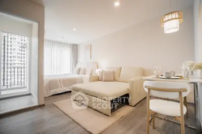 Modern studio apartment with cozy living area and elegant decor, featuring a large window with city view.