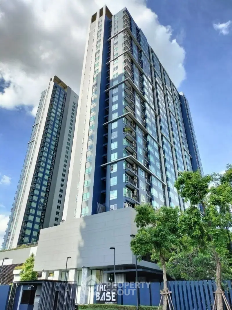 Modern high-rise condominium building with sleek design and lush greenery
