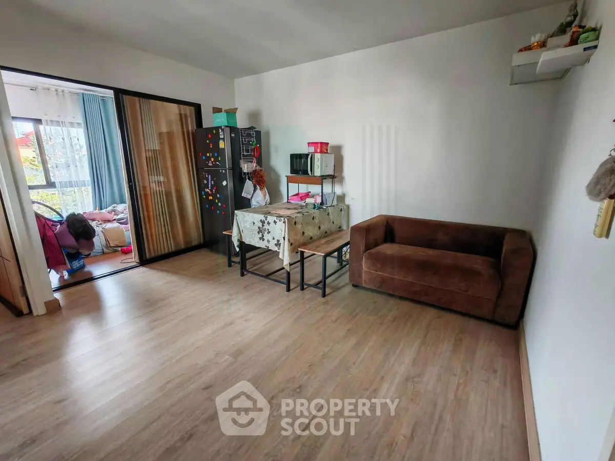 Spacious living room with wooden flooring and cozy seating area, perfect for relaxation and entertaining.