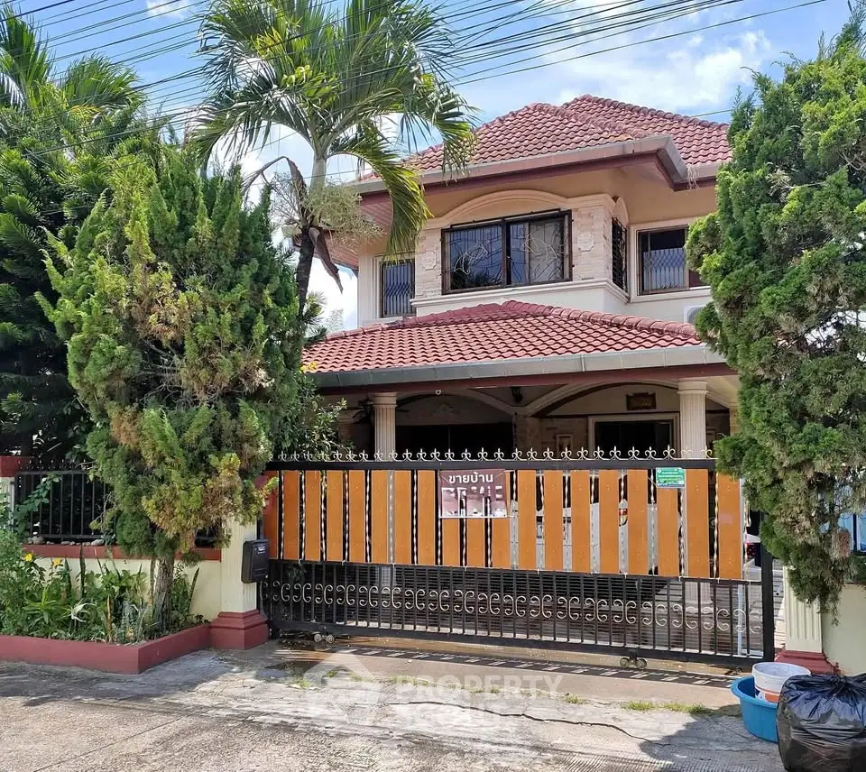 Charming two-story house with lush garden and secure gated entrance.