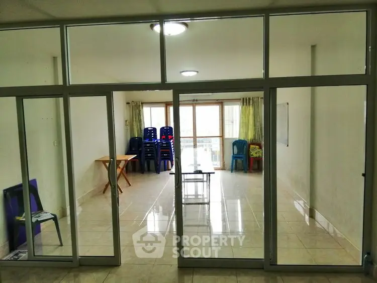 Spacious living room with glass partition and tiled flooring, ideal for versatile interior design.