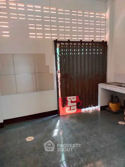 Spacious kitchen with tiled floor and natural light, featuring a closed layout and ample storage space.